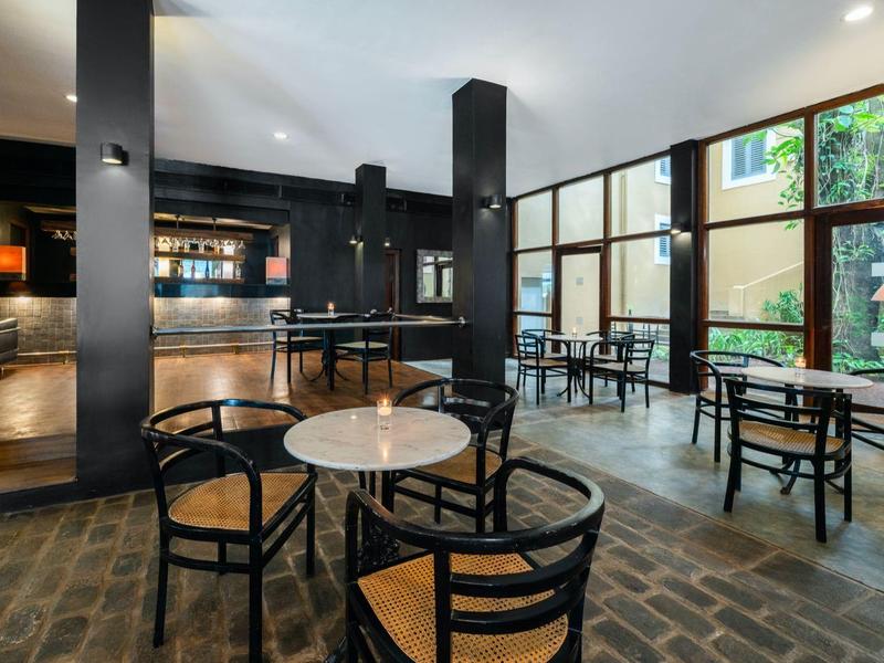 Moderner Caféinnenraum mit schwarzen Möbeln, Marmortischen und großen Fenstern, helles Tageslicht.