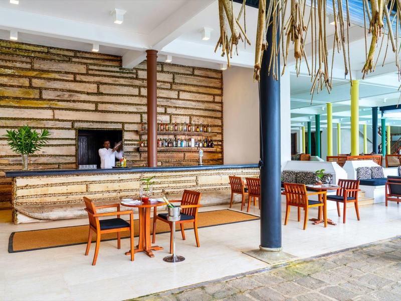 Moderner Hotelbarbereich mit Holztheke und mehreren Stühlen in hellem Raum