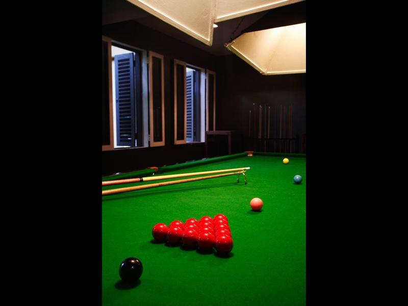 Grüner Billardtisch mit neun roten Kugeln, weißer Spielkugel und braunem Holzhintergrund.