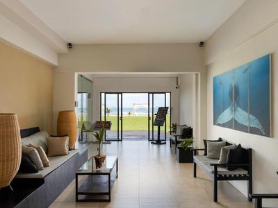 Spazio abitativo moderno con area salotto e vista su terrazza e giardino con vista mare.