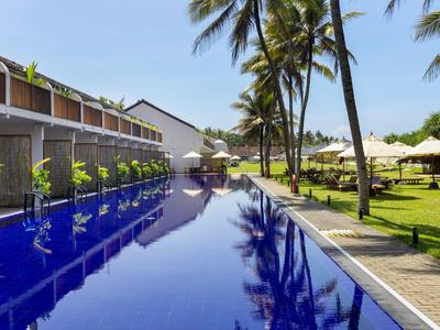Moderner Pool mit klar blauem Wasser, Palmen und Sonnenliegen in einem Resort.