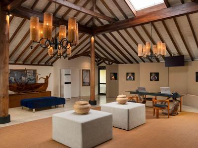 Accogliente lounge dell'hotel con soffitto a travi di legno, mobili moderni e lampadari.