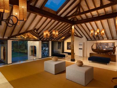 Modernes Wohnzimmer mit Holzdecke, Kamin, Sitzwürfeln und Zugang zum Pool bei Abendlicht.