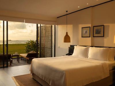 Camera moderna con letto grande e vista su una terrazza e il mare.