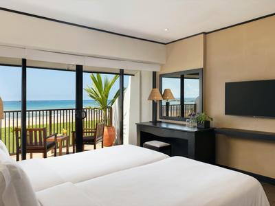 Elegante camera d'hotel con vista mare, terrazza, due letti e arredamento moderno.