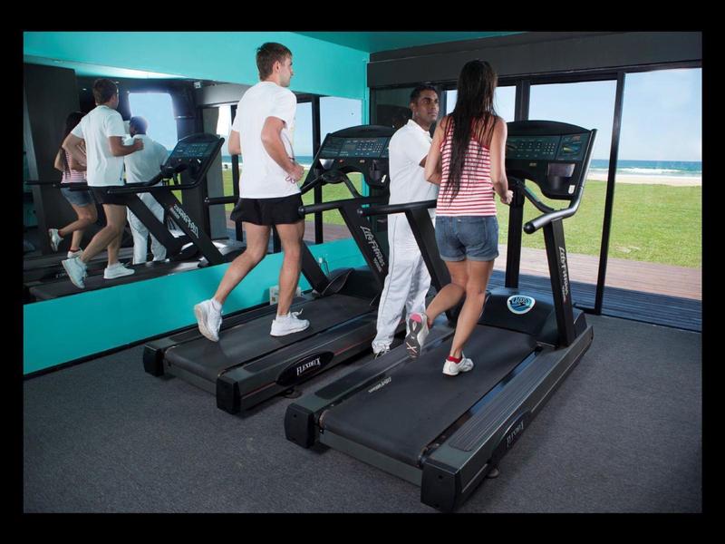 Due persone corrono su tapis roulant in una palestra con vista sul mare.