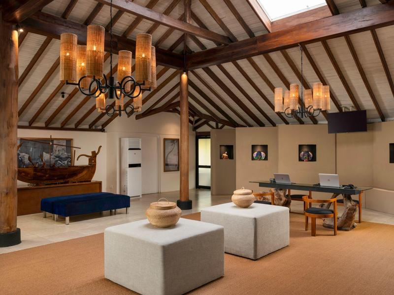 Accogliente lounge dell'hotel con soffitto a travi di legno, mobili moderni e lampadari.