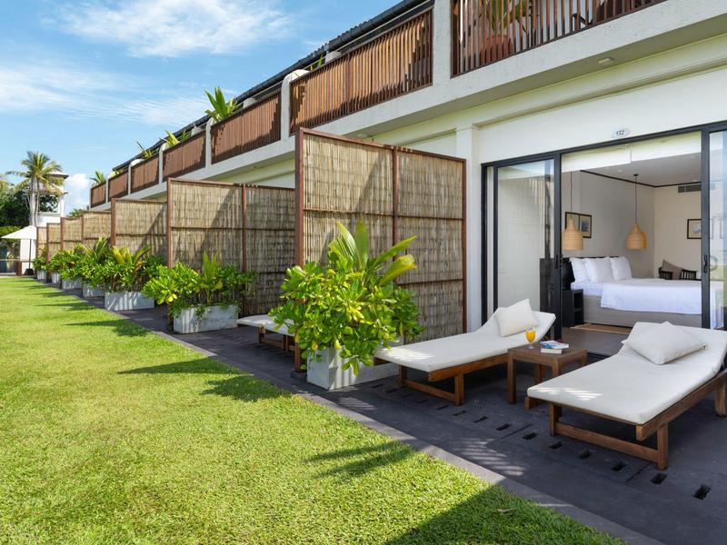 Giardino moderno dell'hotel con lettini e prato verde accanto a terrazze private delle camere.