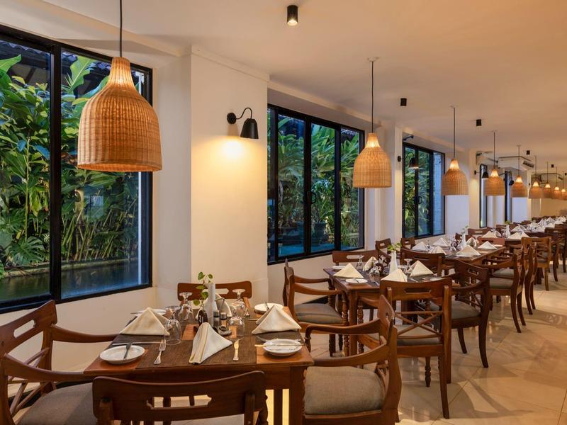 Sala da pranzo luminosa con mobili in legno e grandi finestre con vista sul verde.