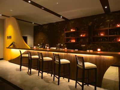 Elegancki bar z drewnianym kontuarem i pięcioma stołkami w ciepło oświetlonym pomieszczeniu