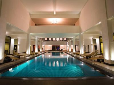 Duży basen wewnętrzny z leżakami i nowoczesnym oświetleniem w eleganckim hotelu.