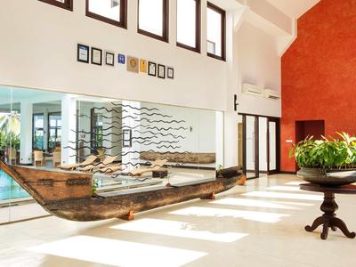 Jasna lobby hotelowa z dużą drewnianą łodzią jako dekoracją i rośliną na stole.