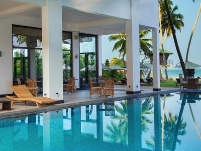 Luksusowy taras z basenem i widokiem na morze, otoczony palmami i leżakami.