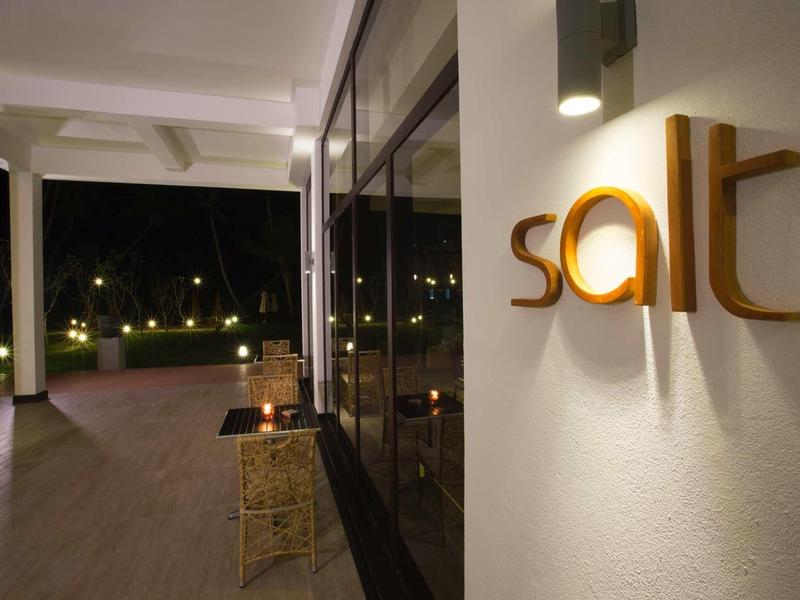 Jasny zewnętrzny obszar hotelu z oświetlonym szyldem "salt" na ścianie nocą.