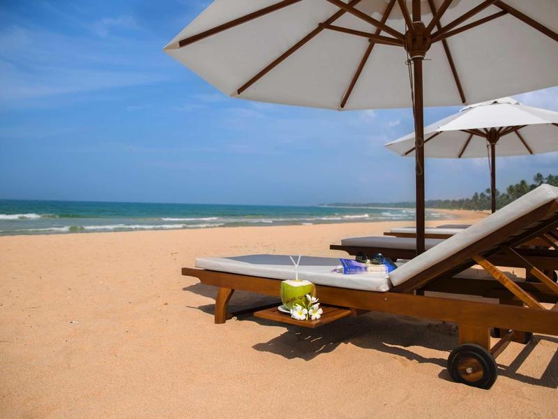 Puste leżaki z parasolami na spokojnej piaszczystej plaży z widokiem na morze.