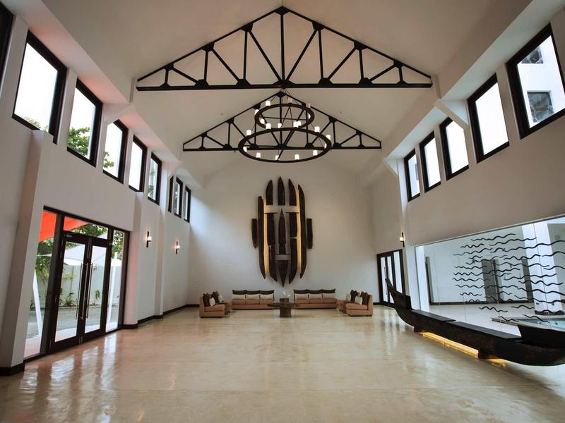 Przestronna jasna lobby hotelowa z wysokimi sufitami, wieloma oknami i nowoczesnym oświetleniem.