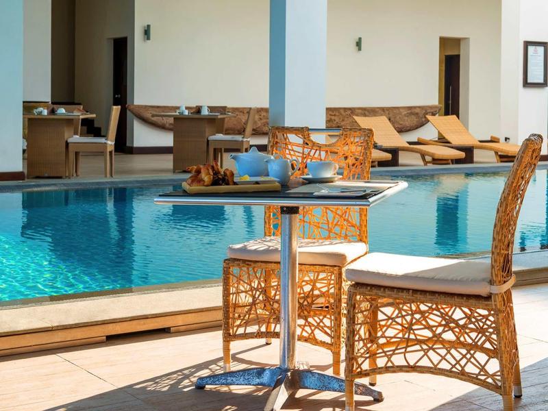 Stolik i krzesło z wikliny obok basenu w słonecznym obszarze hotelu.