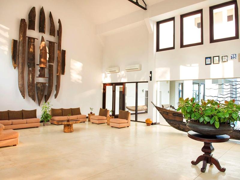 Jasna lobby hotelowa z miejscami do siedzenia i morską dekoracją na ścianie.