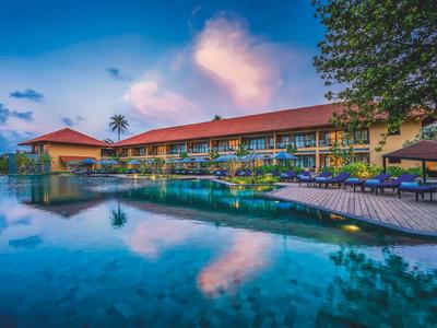 Luxuriöses Resort mit Pool und Liegestühlen bei Sonnenuntergang.