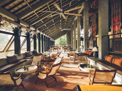 Gemütliche Hotel-Lounge mit Holzmöbeln und großen Fenstern mit Tageslicht.