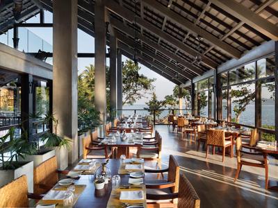 Modernes Restaurant mit großen Fenstern und Bergblick, hübsch gedeckte Tische und Holzstühle.