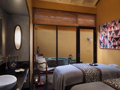 Modernes Hotelzimmer mit zwei Massageliegen, Spiegeln und gemütlicher Atmosphäre.