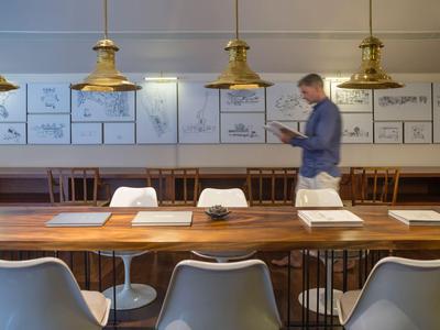 Moderner Besprechungsraum mit Holztisch, weißen Stühlen und hängenden goldenen Lampen