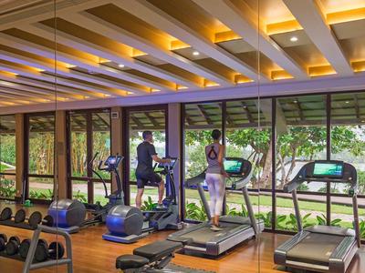 Fitnessraum mit Laufbändern und Gewichten, großer Fensterfront mit Blick ins Grüne