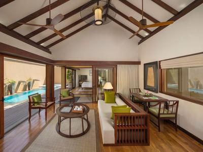 Ein helles Wohnzimmer mit Holzmöbeln und Blick auf einen Pool durch große Glasschiebetüren.