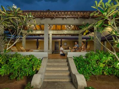 Abendliche Aufnahme eines offen gestalteten Resorts mit beleuchteter Terrasse und tropischen Pflanzen.