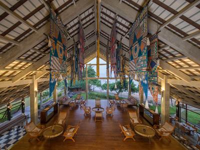 Große offene Lobby mit Holzboden, Rattanmöbeln und bunten Dekorationen im tropischen Stil.