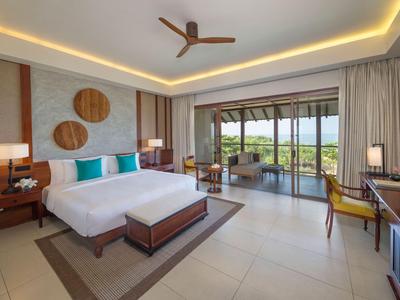 Modernes Hotelzimmer mit Doppelbett, Balkon und Meerblick, stilvollem Holzmobiliar und Deckenventilator.