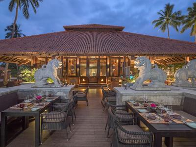 Elegantes Restaurant mit Tischen im Freien und asiatischer Architektur bei Abenddämmerung.