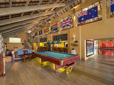 Innenraum mit Billardtisch, Sitzgruppen und internationalen Flaggen an der Wand.