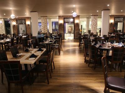 Großer, eleganter Restaurantraum mit Holzboden, gedeckten Tischen und warmem Licht.