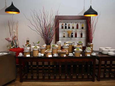 Tisch mit Honiggläsern, Flaschen, zwei Lampen und Holzregal mit Flaschen vor weißer Wand.