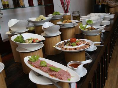 Mehrere weiße Schalen voller verschiedenes Essen sind auf hölzernen Ständern aufgereiht.