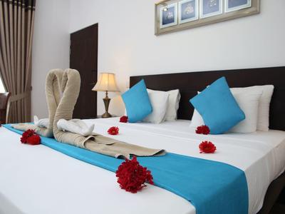 Schön dekoriertes Doppelbett mit blauen Kissen, roten Rosen und Handtüchern in Schwanform.