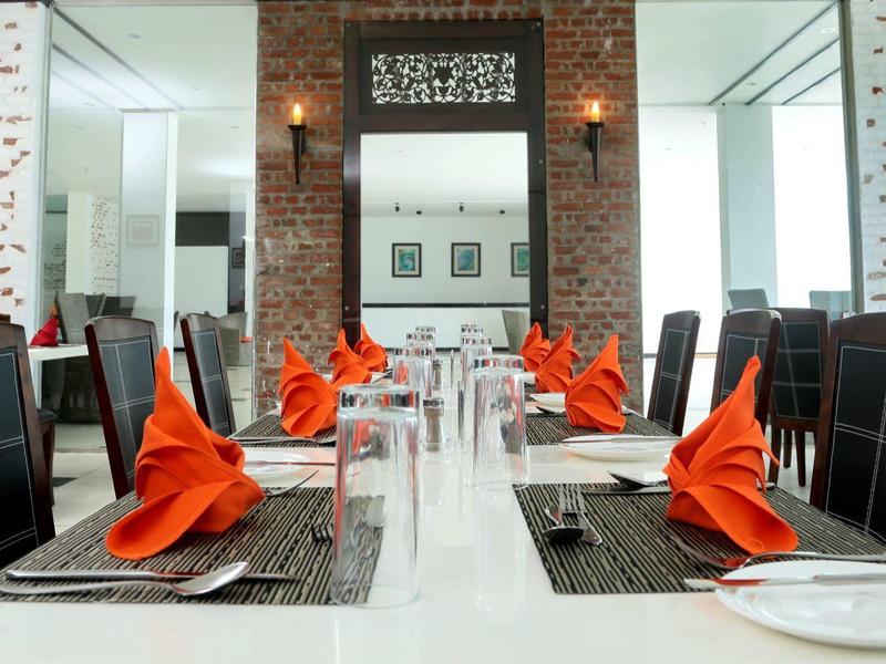 Modernes Restaurant mit weißem Tisch, schwarzen Stühlen und orangefarbenen Servietten.