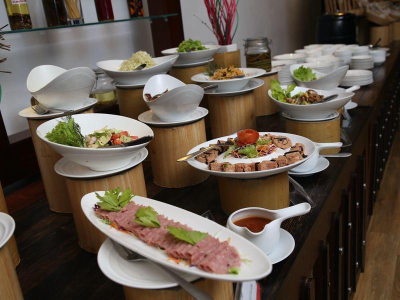 Mehrere weiße Schalen voller verschiedenes Essen sind auf hölzernen Ständern aufgereiht.