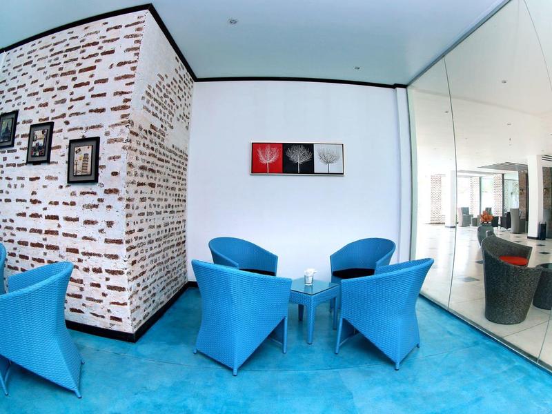 Moderner Wartebereich mit blauen Sesseln, Glastisch, weißer Wand und Spiegelwand.