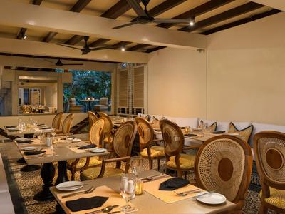 Elegantní restaurace s dřevěnými židlemi a prostřenými stoly v teplém osvětlení.