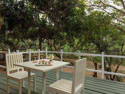 Dřevěný stůl se židlemi na terase s výhledem na zelené stromy