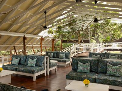 Světlá lounge s pohodlnými pohovkami, rostlinami a velkými okny s výhledem ven.