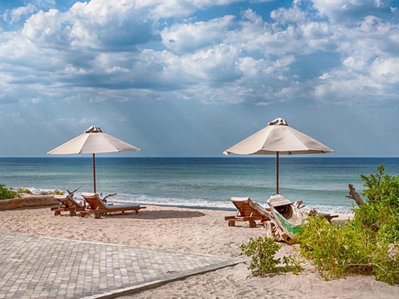 Due ombrelloni con sdraio su una spiaggia tranquilla sotto un cielo nuvoloso.