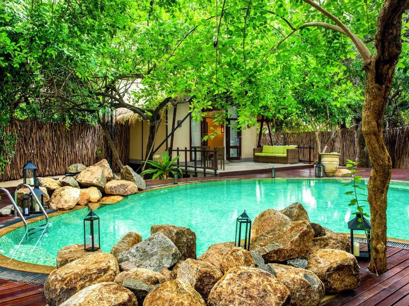 Area piscina idilliaca con pietre naturali e vegetazione rigogliosa.