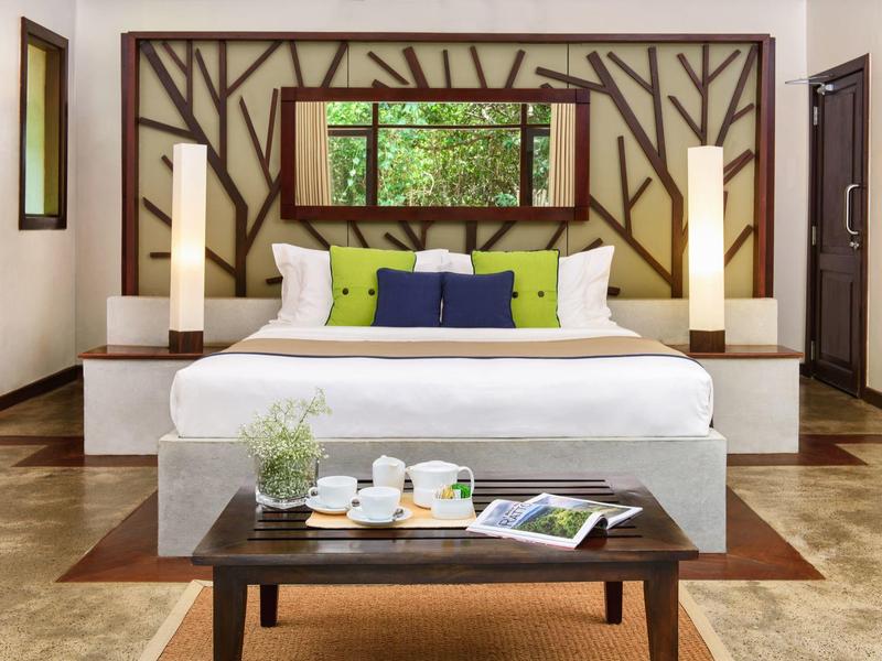 Camera d'hotel moderna con letto grande, testiera decorativa e tavolo con servizio da tè.