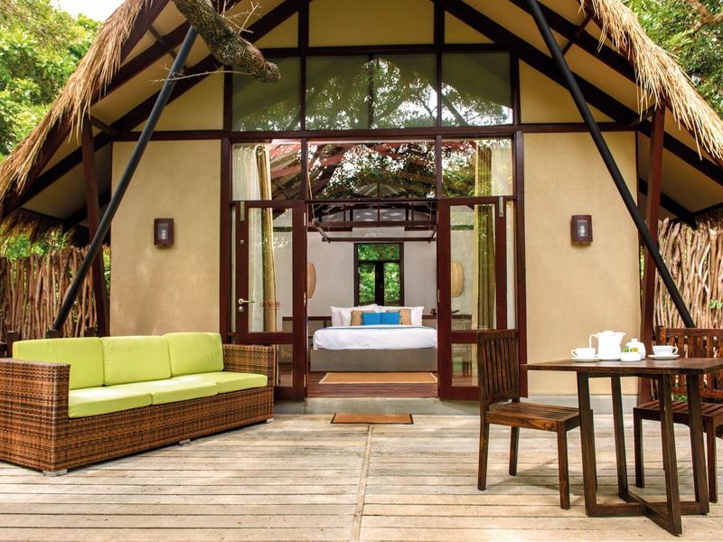 Accogliente patio con divano e zona pranzo davanti a una capanna con vista sulla camera da letto.