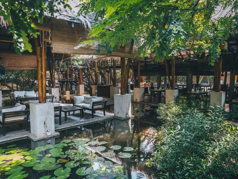 Area esterna dell'hotel con stagno, posti a sedere e verde rigoglioso.