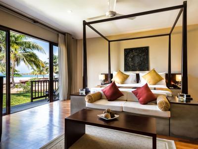 Chambre d'hôtel moderne avec lit à baldaquin et vue sur la mer à travers de grandes fenêtres en verre